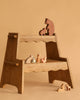 An Ostheimer Handmade Wooden Woodland Animals Set, featuring bears, a rabbit, a squirrel, a fox, and a deer, is displayed on a wooden step stool against a beige background.