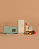 The Maileg Kitchen Set features a green sink and oven, cream refrigerator, blender, toaster, vegetables, fruit, and a striped rug—miniature accessories arranged on a simple beige background.