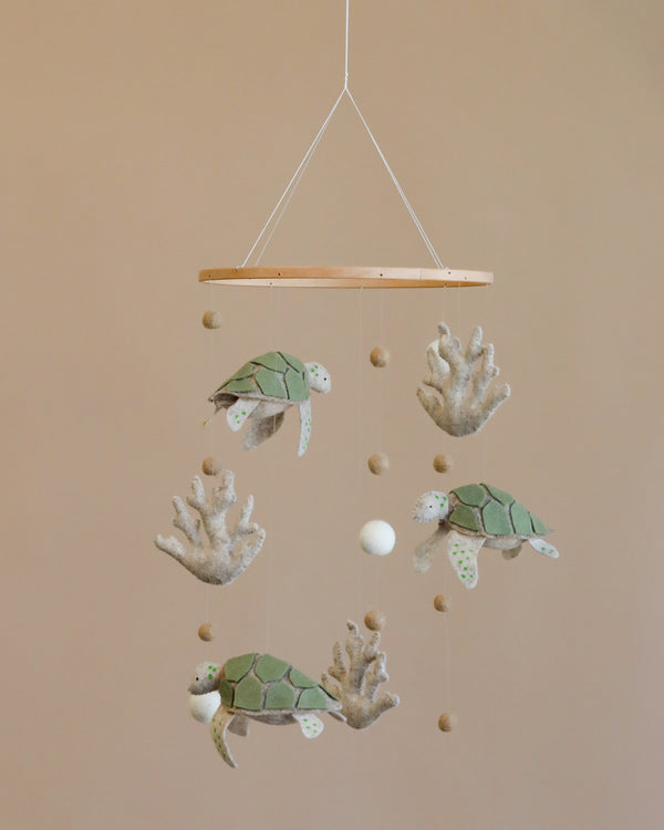 A Handmade Mobile - Ocean Turtles - Final Sale featuring four plush sea turtles and several small felt balls suspended from a wooden ring against a light beige background.