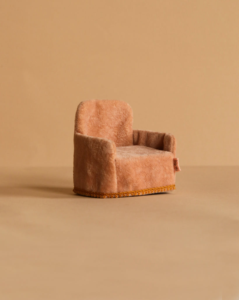 The Maileg Cozy TV Time Set features a small, plush pink armchair with rounded arms and back, yellow trim at the base, and a soft texture. Placed on a beige background, it's perfect for a Maileg Big Sister Mouse.