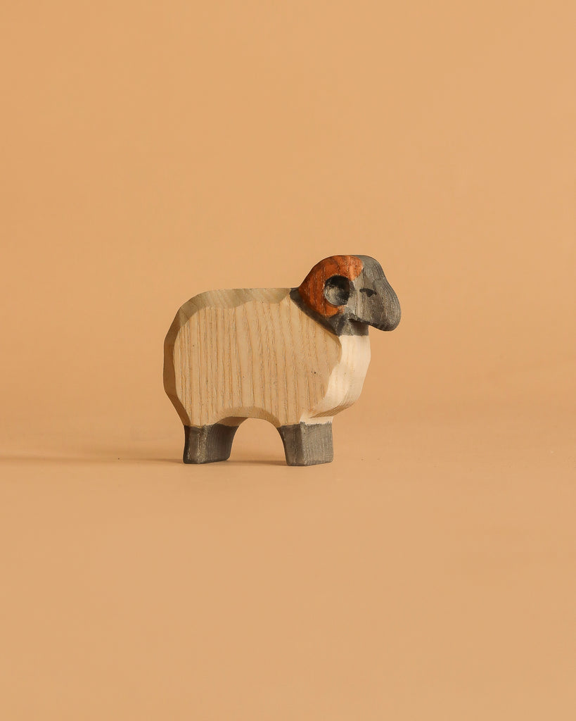 This ram figurine from the Ostheimer Handmade Wooden Farm Animals Set is hand-carved from sustainable wood, featuring dark legs, a black face, and brown curved horns, inspired by classic Ostheimer toys.