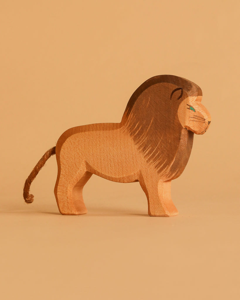 A lion from the Ostheimer Handmade Wooden Safari Animals Set, featuring a dark brown mane and tail, stands on a beige background. Its simple, hand-carved design highlights the charm of handcrafted wooden toys with minimal painted details.
