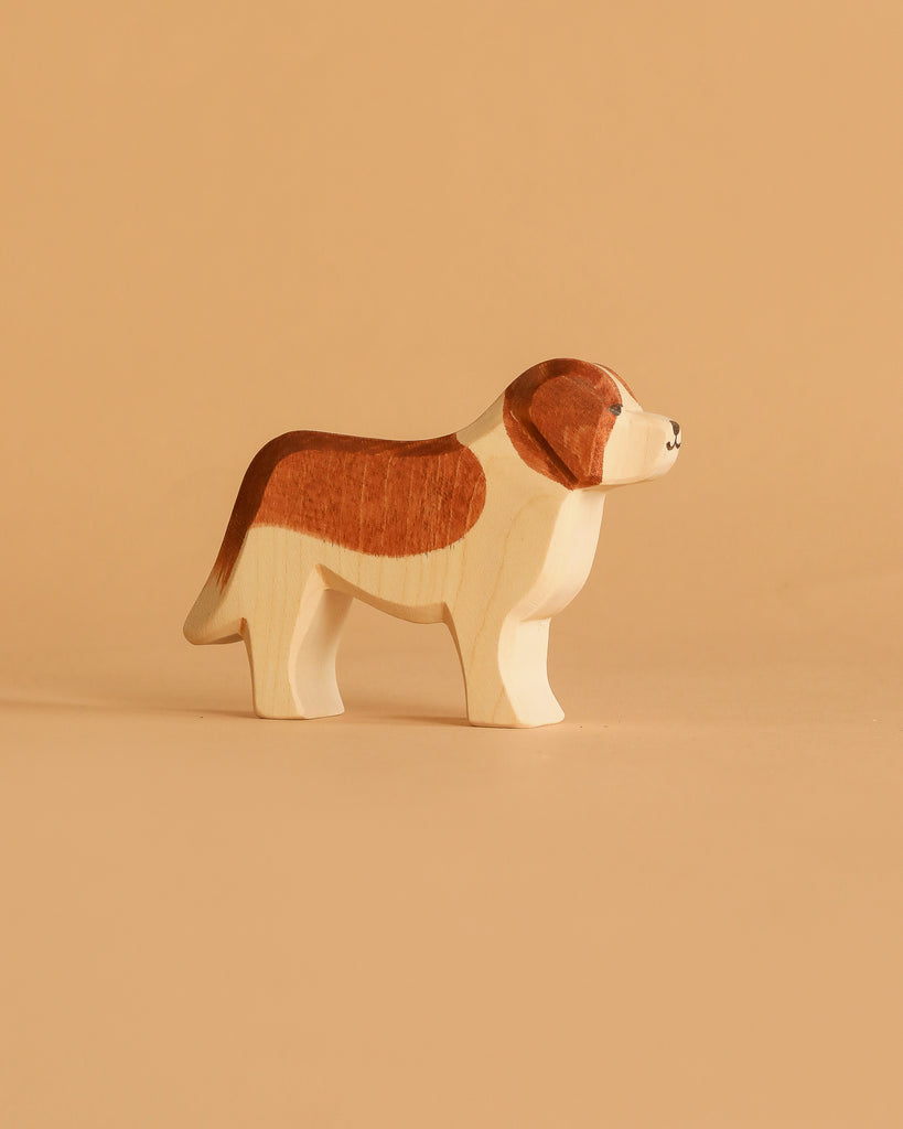 The Ostheimer Saint Bernhard Dog is a handcrafted wooden toy, painted with brown and white patches, set on a light beige surface against a matching background—ideal for imaginative play and echoing classic Ostheimer design.