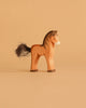 The Ostheimer Brown Horse / Colt, a handcrafted wooden toy with a painted mane and tail, stands on a beige surface against a matching background—an enduring example of sustainable play.