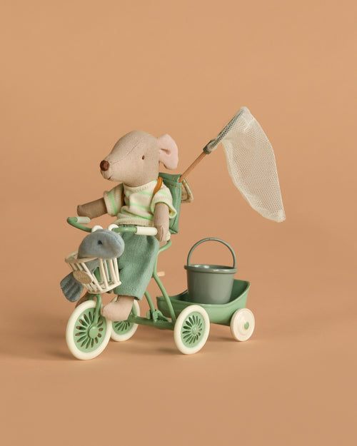 The Maileg Big Brother Gone Fishing Set features a tricycle mouse riding a mint green bike with a basket, trailer holding a bucket, fishing net set, and stuffed animal, shown against a plain beige background.