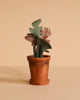 The Maileg Cozy Corner Set features a small terracotta pot with a plant that has green and floral-patterned fabric leaves, set against a beige background—perfect for pairing with the Maileg Vintage Floor Lamp to complete a charming miniature scene.