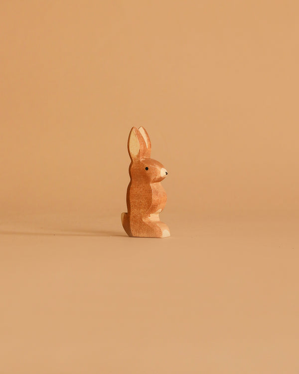 The Ostheimer Rabbit - Ears Up is a small, light brown wooden figurine that stands upright on a beige background—perfect for imaginative play and showcasing beautiful handcrafted toy design.