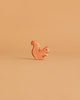A small squirrel figurine from the Ostheimer Handmade Wooden Woodland Animals Set sits on a plain, light brown background, its minimalist wooden design blending subtly with its surroundings.