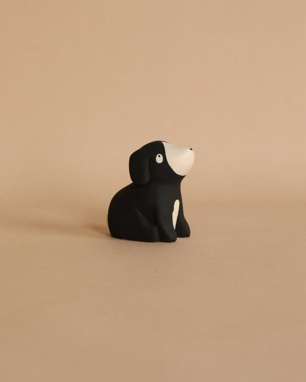 A small, black Handmade Tiny Wooden Beagle Dog with a white snout and a whimsical expression, sitting against a plain light beige background.