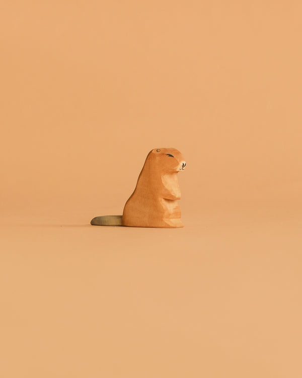 The Ostheimer Beaver - Sitting figurine, featuring a gray tail, rests against a light orange background—a charming handcrafted wooden toy ideal for imaginative play.