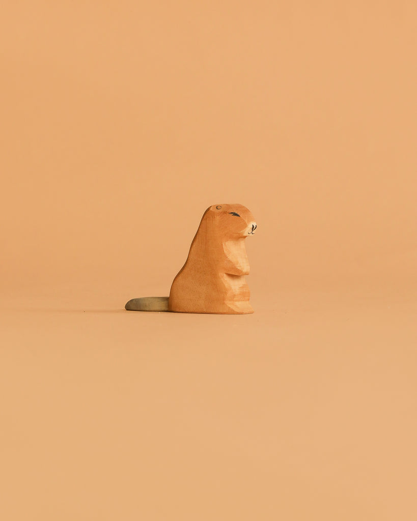 The Ostheimer Beaver - Sitting figurine, featuring a gray tail, rests against a light orange background—a charming handcrafted wooden toy ideal for imaginative play.