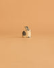 The Ostheimer Black & White Rabbit - Sitting is a charming figurine on a peach background, ideal for sparking imaginative play and pairing perfectly with other Ostheimer toys.