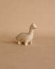 A Handmade Tiny Wooden Brachiosaurus with a simple design and a smiling face, standing on a plain beige background.