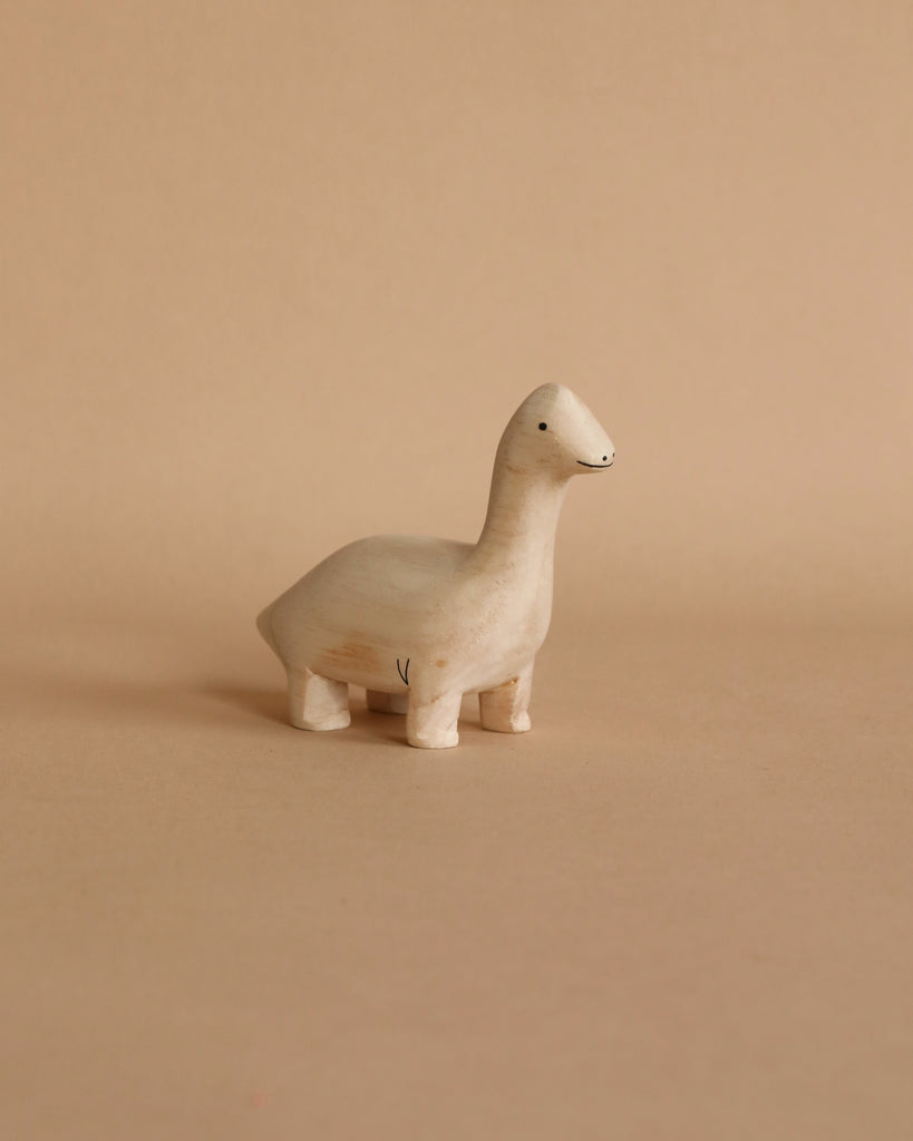 A Handmade Tiny Wooden Brachiosaurus with a simple design and a smiling face, standing on a plain beige background.