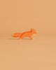 The Ostheimer Small Fox - Running is a minimalist wooden figurine in orange and white, shown on a light orange background—ideal for imaginative play or to add to your handcrafted wooden toys collection.