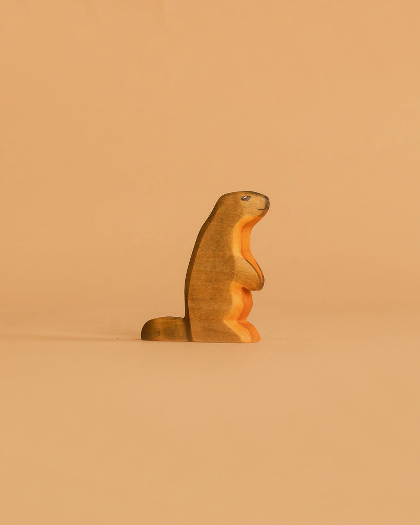 The Handmade Holzwald Marmot, a small wooden figurine, stands upright against a plain light brown background—an adorable and eco-friendly addition to any sustainable toy collection.