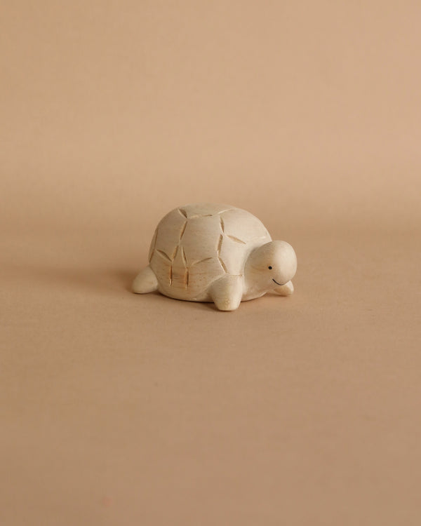 A small Handmade Tiny Wooden Forest Animals - Turtle figurine with subtle cracks displayed on a plain beige background.