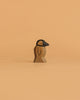 The Handmade Holzwald Penguin, Small, features a carved wooden body with a black beak and head, standing upright on a light orange background—a delightful addition to any sustainable wooden toy collection or for imaginative play.