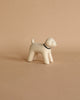 A small, handcrafted figurine of a Poodle with a simple design crafted from Albizia wood, featuring a dark collar, standing against a plain, light beige background.