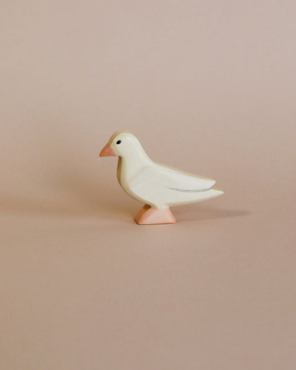 A minimalist, high-quality Handmade Holzwald Dove with a light pink beak, standing against a soft beige background.