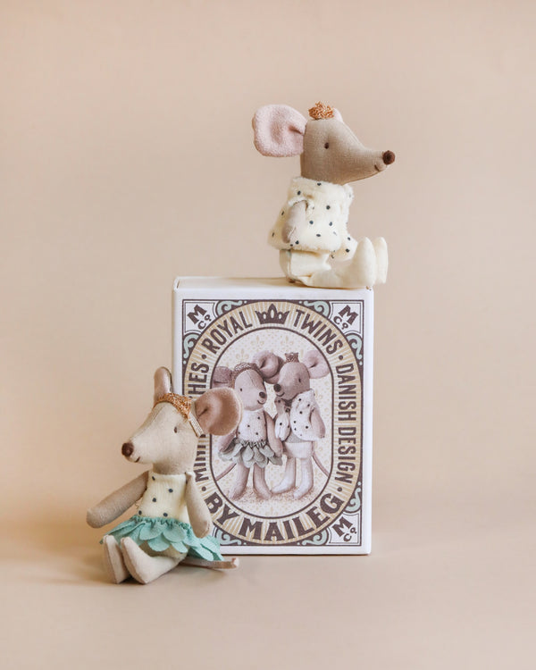 Three adorable, handmade Maileg Royal Twins in Box, Little Brother and Sister, each uniquely dressed including one in a dotted vest, perched on top of and beside a custom matchbox against a soft beige background.