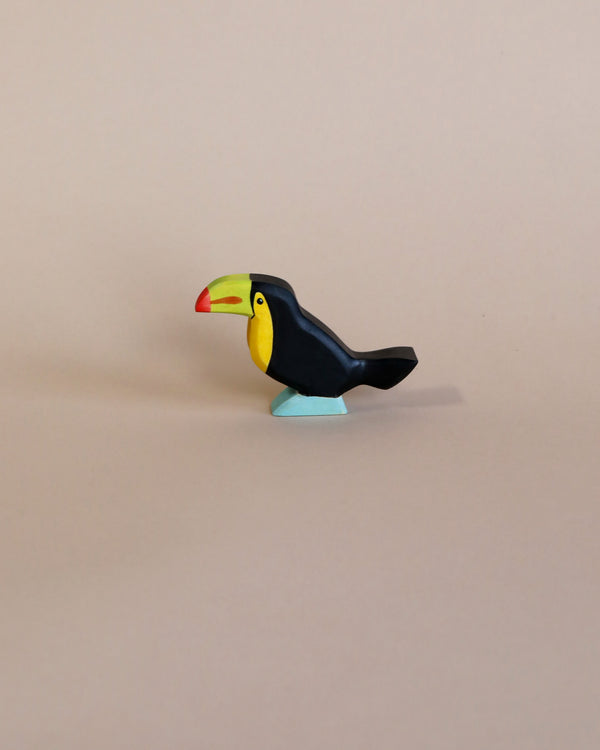 A colorful, high-quality Handmade Holzwald Toucan Bird toy with a prominent red and yellow beak and dark blue body, positioned against a plain light beige background.