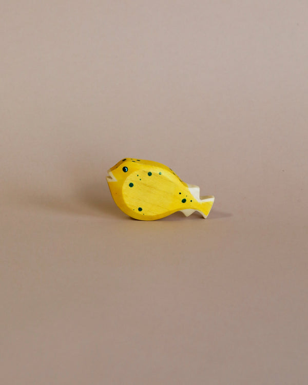 A high-quality Handmade Holzwald Pufferfish toy painted yellow with black spots, positioned against a plain beige background.