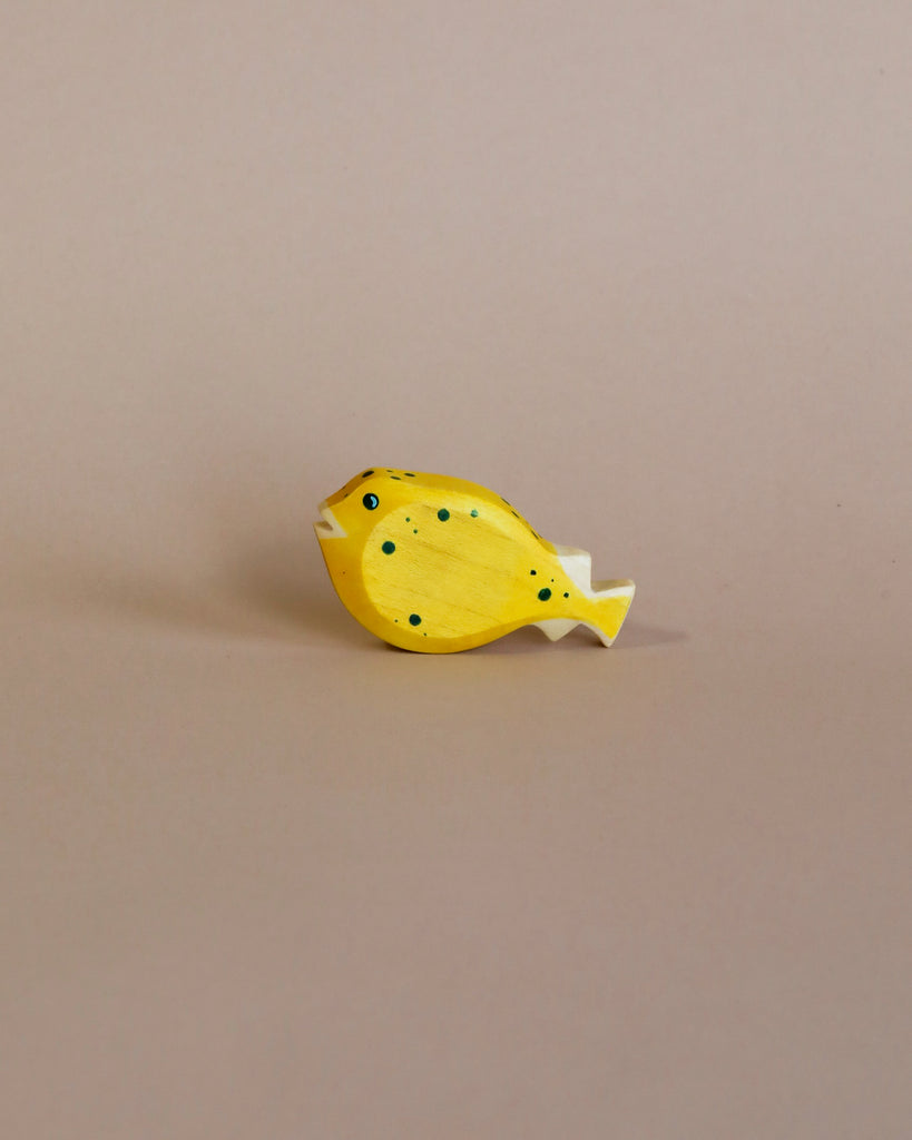 A high-quality Handmade Holzwald Pufferfish toy painted yellow with black spots, positioned against a plain beige background.