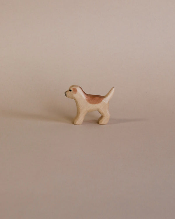 A small, high-quality Handmade Holzwald Golden Retriever Puppy figurine, with a light brown and white coat, standing on a plain beige background.