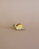 A Handmade Holzwald Small Snail with a shiny gold shell and a matte white body, positioned on a smooth light tan background by Holzwald Brand.