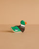 A Holztiger Handmade Wooden Woodland Animals Set features a small, handcrafted wooden duck figurine painted green, orange, brown, and white. It sits on a beige surface with a matching background—ideal for open-ended play.