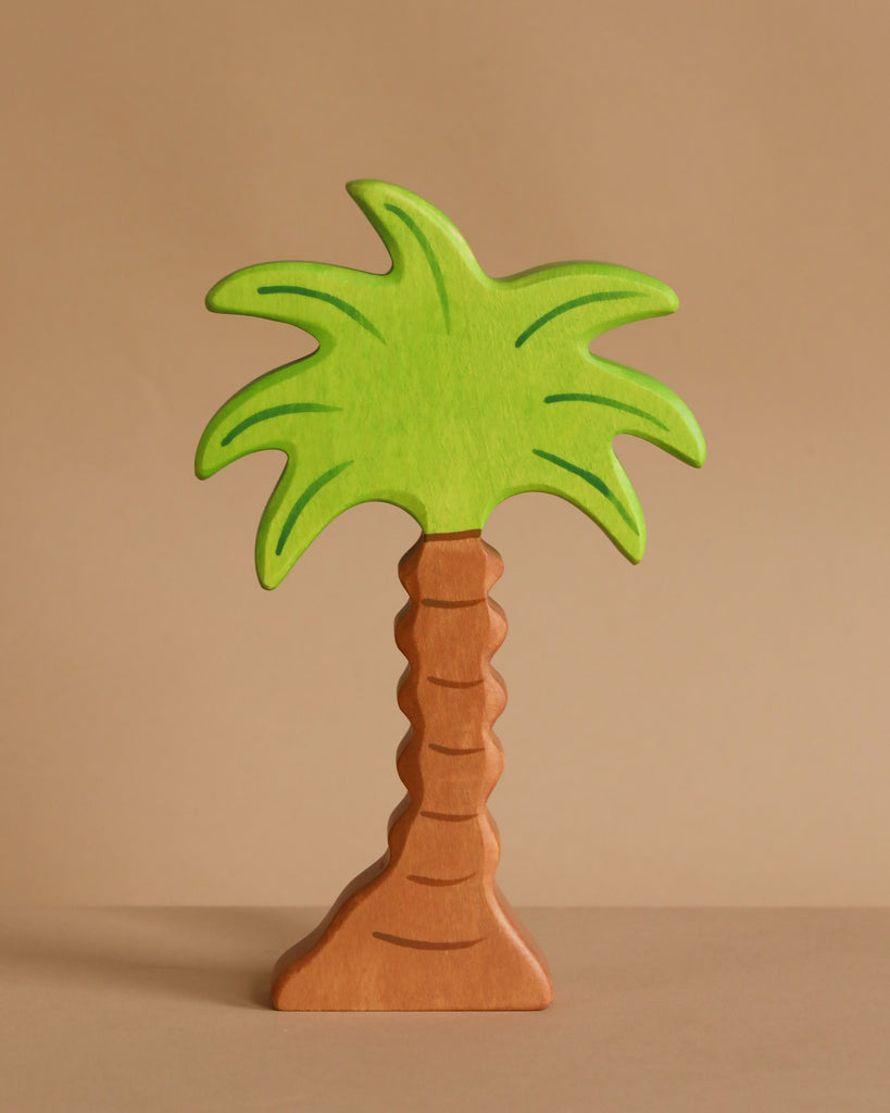 A handcrafted wooden palm tree from the Holztiger Handmade Wooden Safari Animals Set, featuring a light brown trunk and vivid green leaves, stands upright against a beige background—perfect for imaginative play or collection.