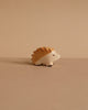 A small, handcrafted Holztiger Hedgehog wood figurine with natural tones rests on a beige surface and background, evoking the charm of European-made HOLZTIGER figures.
