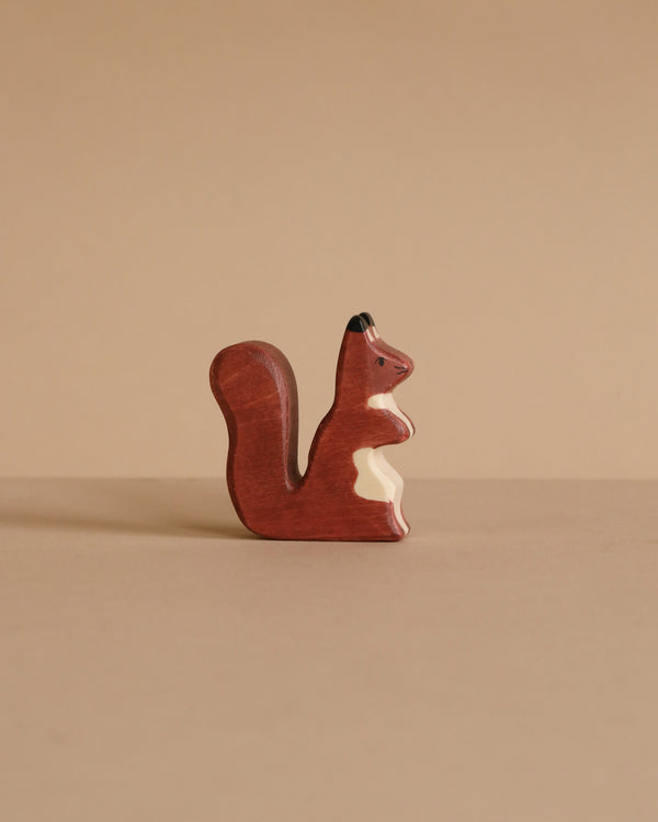The Holztiger Squirrel, brown is a small handcrafted figurine made from maple and beech wood, featuring a white chest patch and shown standing upright against a plain beige background.