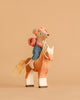 The Maileg Big Sister Horseback Adventure Set features a hiker mouse in denim pants, headscarf, and pink backpack riding a handmade wooden horse—an adorable scene perfect for fans of artisanal toys.