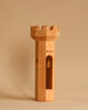 A Maileg Royal Tower Set piece, shaped like a chess rook with smooth edges and window-like openings, stands upright against a plain beige background.