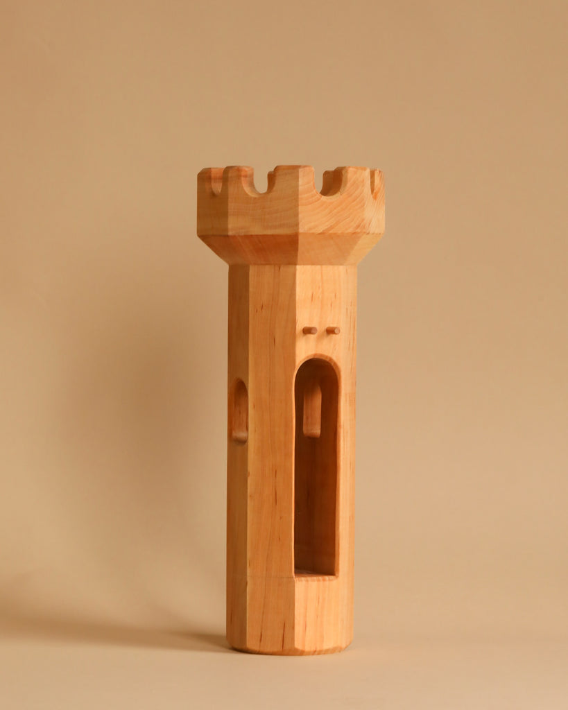 A Maileg Royal Tower Set piece, shaped like a chess rook with smooth edges and window-like openings, stands upright against a plain beige background.