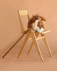 A wooden chair displays the Hobbyhorse - Lion, featuring a plush lion head and brown stick, ready for safari play against a simple beige background.