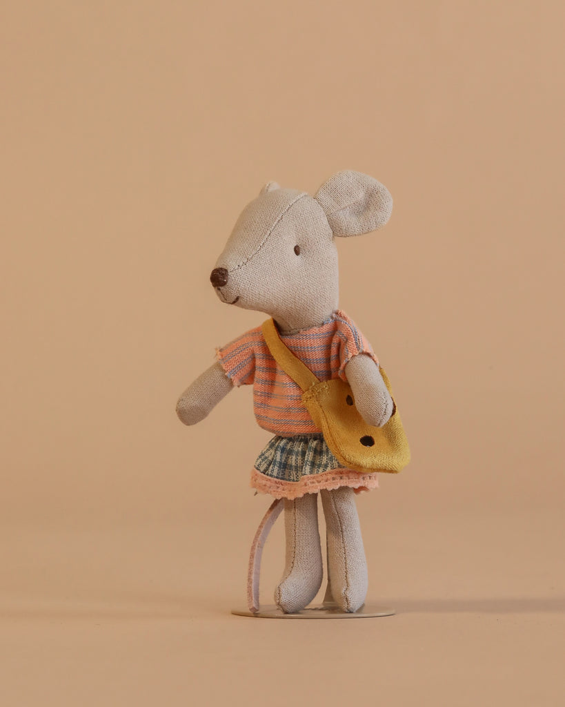 The Maileg Little Brother and Sister Bedroom Set features a small gray mouse in a pink striped shirt, plaid skirt, and yellow bag standing upright against a plain beige background.