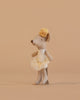 The Maileg Ballerina Mouse, Little Sister - Off White, is a small gray mouse in a cream tutu with a yellow flower headband, standing upright against a plain beige background.