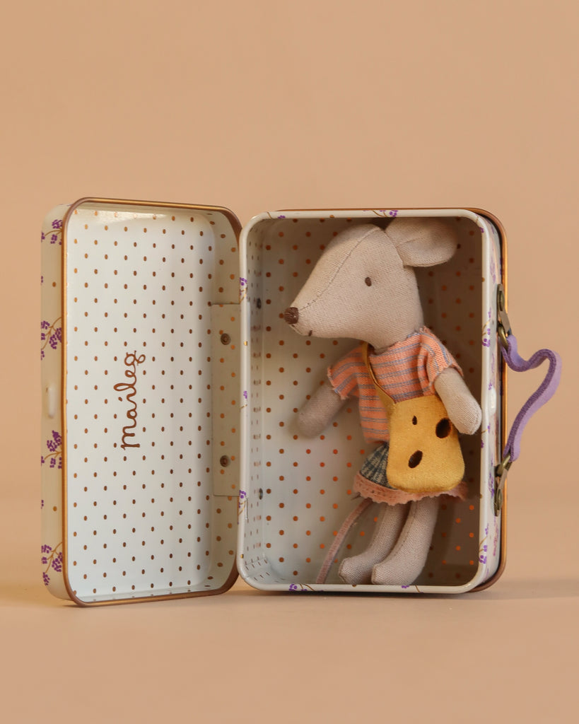 The Maileg Little Sister On the Go Suitcase Set includes a mouse doll with a striped shirt, skirt, and yellow purse, sitting in a polka-dot and floral suitcase. Contains small parts; not suitable for children under three.