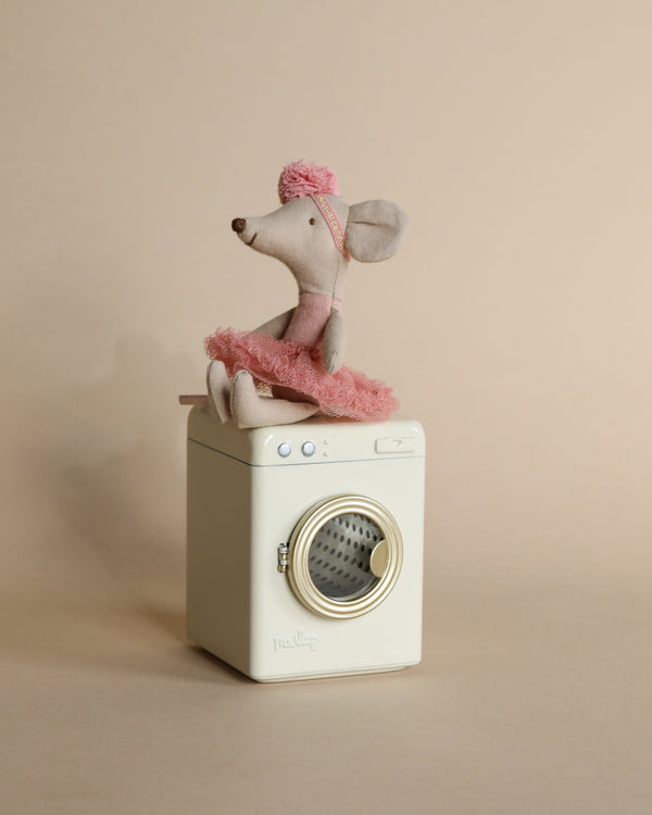 A plush toy mouse family wearing pink tutus and matching hats, sitting on top of a Maileg Washing Machine For Mice against a neutral beige background.