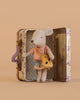 The Maileg Little Sister On the Go Suitcase Set features a mouse in a striped shirt, plaid skirt, and yellow bag next to an open floral suitcase with a polka dot interior. Contains small parts; not suitable for young children.