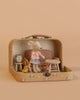 The Maileg Little Sister Mini House Set features a mouse in a pink shirt and blue skirt with a sofa bed, table, chair, clock, and toy cheese set inside an open Maileg suitcase on a beige background.