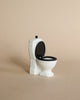 A small, white Maileg Bathroom Set toy with a black seat and open lid sits against a beige background—a charming accessory for the Maileg Wellness Accessories collection.