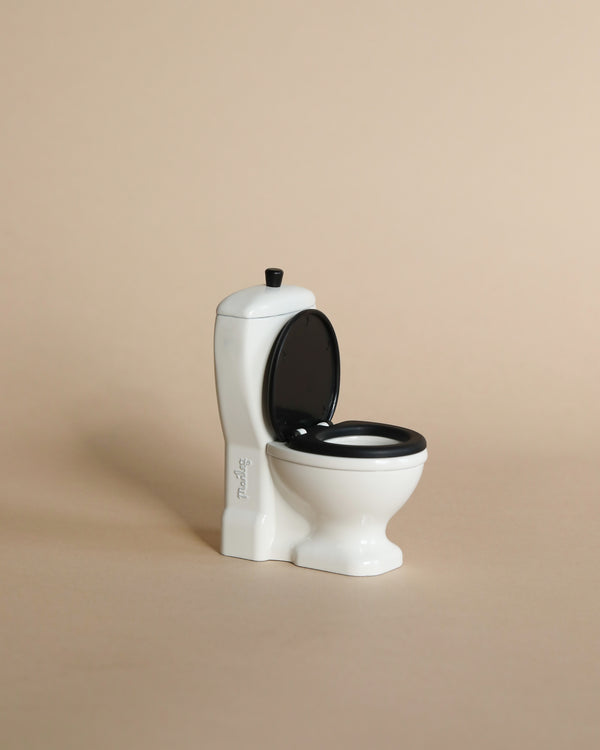 Mini white toilet with back lid. Photographed against beige background. 