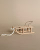 The Maileg Gingerbread House Christmas Set features a cozy wooden sled with metal handles and a white rope, perfect for your Maileg Mouse to enjoy beside the Christmas tree.