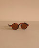Minikane Doll Accessories | Harry Sunglasses feature round brown lenses and tortoiseshell frames, displayed on a beige surface—perfect stylish accessories for your Minikane doll.