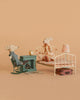 The Maileg Grandma and Grandpa Bedroom Set features two mice relaxing in a cozy miniature room with vintage furniture and charming accessories like a rocking chair, fireplace, bed, lamp, clock, rug, and suitcase against a beige background.