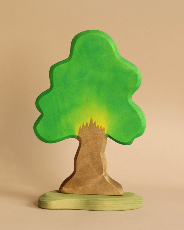 The Ostheimer Oak Tree is a handcrafted wooden toy featuring a broad green canopy and a brown trunk, standing on an oval base. This tree has a simplified design with smooth edges and a natural finish, meticulously crafted from sustainably sourced materials.